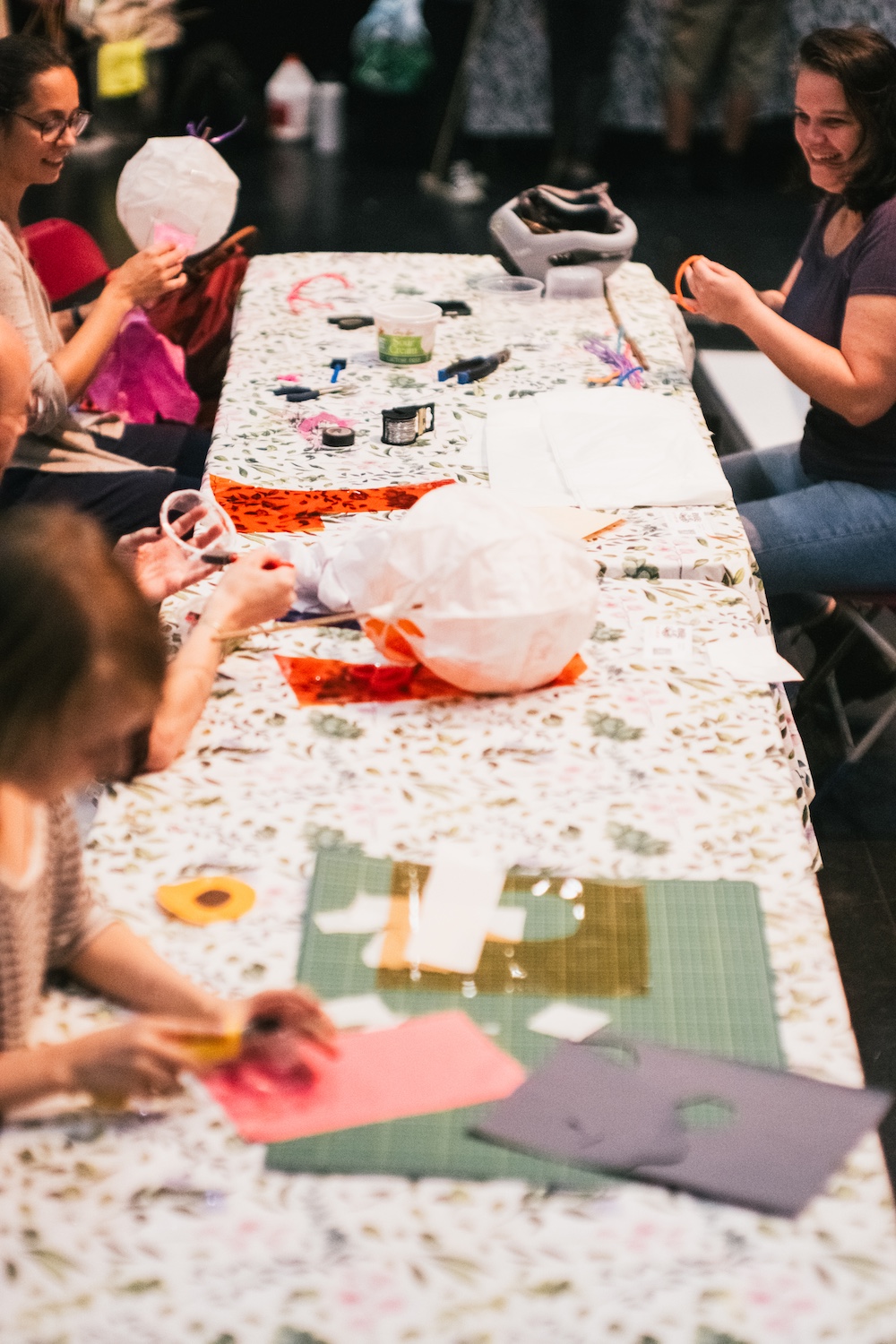 Groupe d'adultes fabriquant des lanternes en papier autour d'une table, lors d'un atelier de création de Rivières de Lumières.